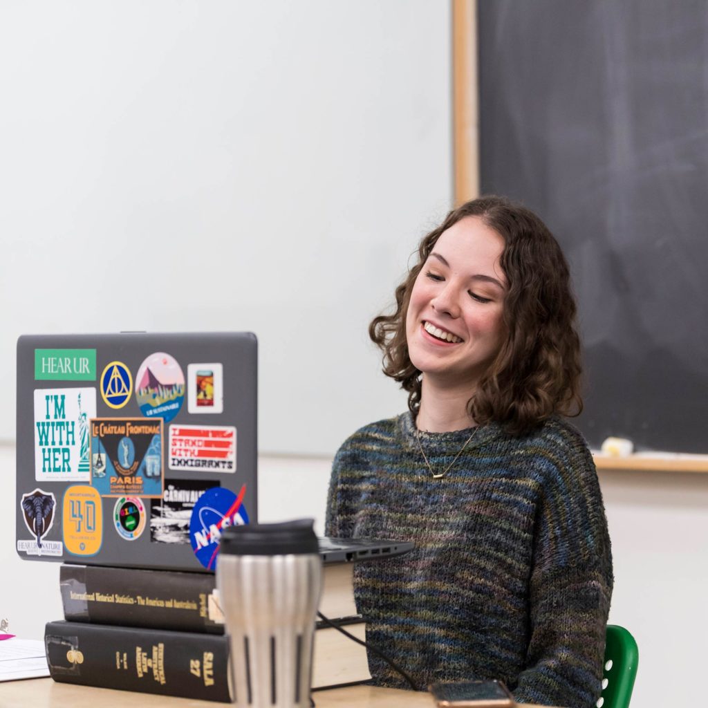 A person smiling at their laptop screen.